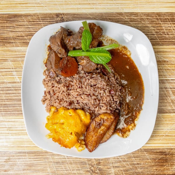 A plate of brown stew chicken, rice and peas, macaroni and cheese, and fried plantain.